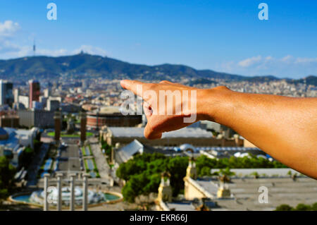 Un giovane uomo caucasico punti il dito verso la città di seguito dalla collina di Montjuic a Barcellona, Spagna Foto Stock