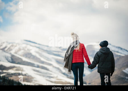 Un fratello e una sorella in piedi a fianco a fianco nella neve, vista posteriore. Foto Stock