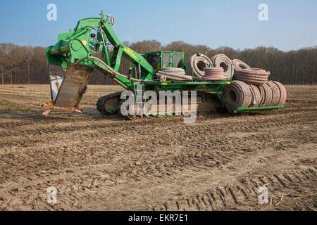 Il drenaggio scavatrincee / tile aratro con carico di tubazioni di drenaggio lavora su terreni agricoli Foto Stock