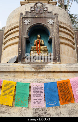 Un chorten stupa e con una statua del Buddha con bandiere di preghiera presso il Complesso del tempio di Mahabodhi a Bodhgaya, Foto Stock
