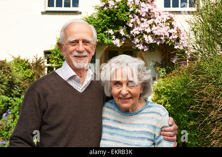 Coppia senior in piedi al di fuori del grazioso cottage Foto Stock
