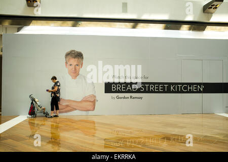 Singapore il 14 aprile 2015. Una donna con una carrozzina sta in piedi di fronte ad un poster che vanta lo chef Gordon Ramsay che apre un ristorante a Singapore Credit: amer ghazzal/Alamy Live News Foto Stock