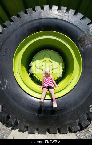 Una bambina si siede sul pneumatico della più grande del mondo Carrello; Sparwood, British Columbia, Canada Foto Stock