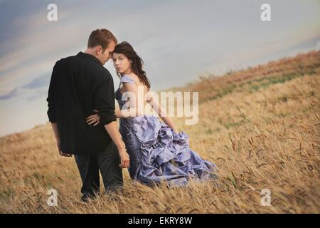 Edmonton, Alberta, Canada; un paio in piedi in un campo e la donna indossa un abito formale Foto Stock