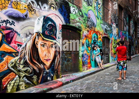 I turisti rappresentano per gli snapshot in Melbourne's Hosier Lane è un celebre punto di riferimento qualora legale street art decora le pareti. Foto Stock