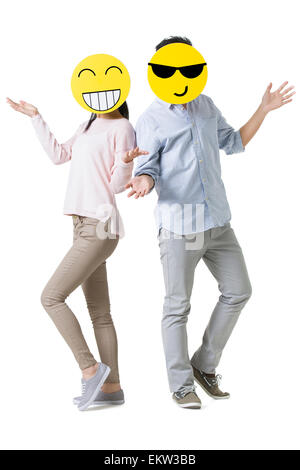 Coppia giovane con il cartoon emoticon volti nella parte anteriore delle loro facce Foto Stock