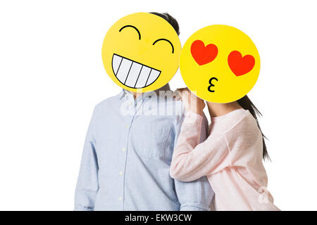 Coppia giovane con il cartoon emoticon volti nella parte anteriore delle loro facce Foto Stock