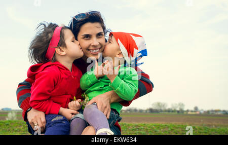 Due bambine di baciare la loro madre Foto Stock