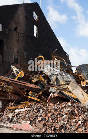 Fire danneggiato edificio con parete esterna rimanendo in piedi e il crollo del tetto con travi e macerie accatastate Cardiff Wales UK Foto Stock