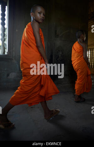 SIEM REAP, Cambogia - 30 ottobre 2014: il Principiante i monaci buddisti in arancione vesti camminare a piedi nudi nei corridoi bui a Angkor Wat. Foto Stock