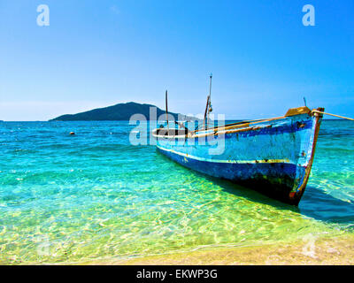 Una barca solitaria sulla riva di Cayos Cochinos, Honduras. Foto Stock