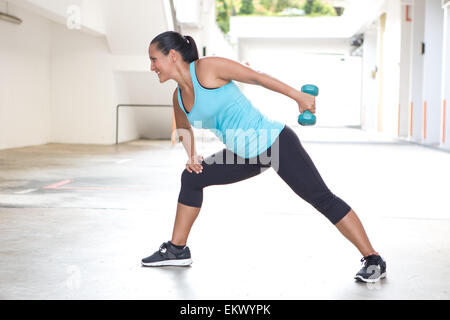 Bellissimo sport donna in blu con il manubrio facendo tricipiti indietro esercizio di estensione Foto Stock