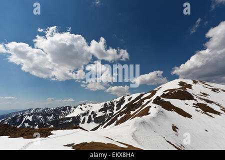 Il sole e il blu cielo nuvoloso sopra la molla tatry montagne, con resti di neve Foto Stock