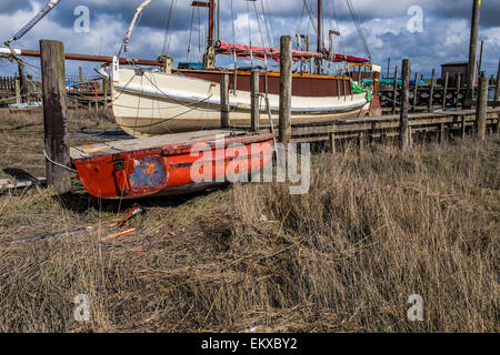 Vecchie barche ormeggiate lungo il fiume, in riva al fiume con una barca a remi nella parte anteriore della barca, terra asciutta, ormeggiata Foto Stock