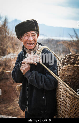 Naxi uomo cinese porta cestello; Lijiang, nella provincia dello Yunnan in Cina Foto Stock