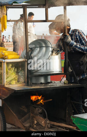 Un ragazzo di bollitura e vendere le pannocchie di granoturco in Kep, Cambogia, in Asia. Foto Stock