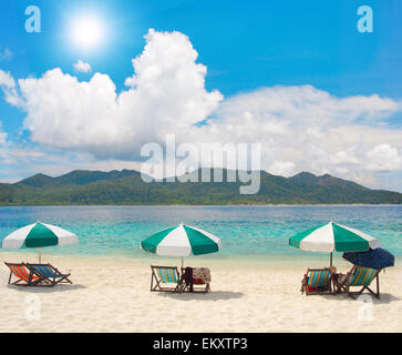 Sedie a sdraio e ombrelloni su una spiaggia tropicale Foto Stock