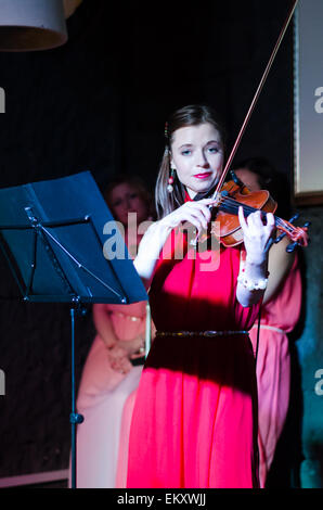 Un concerto di tre donna (ragazze) in rosa e rosso abiti a Minsk Loft Club, due violini + cantante Foto Stock