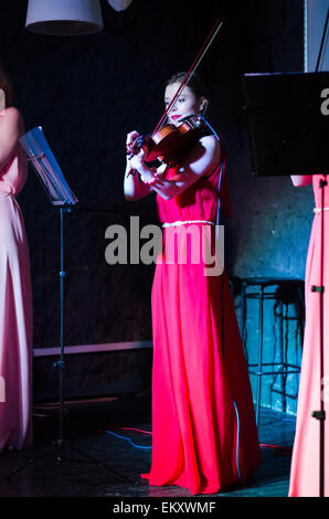 Un concerto di tre donna (ragazze) in rosa e rosso abiti a Minsk Loft Club, due violini + cantante Foto Stock