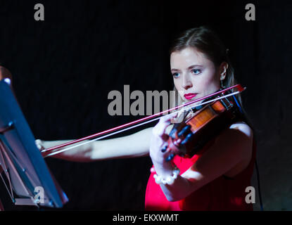 Un concerto di tre donna (ragazze) in rosa e rosso abiti a Minsk Loft Club, due violini + cantante Foto Stock