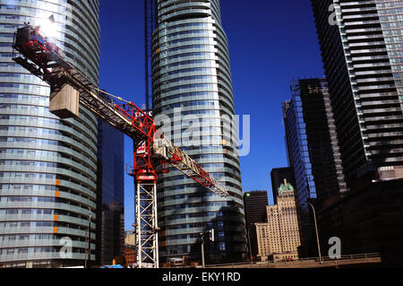 Un rosso di gru a torre e nel mezzo di un gruppo di edifici alti nel centro di Toronto Foto Stock