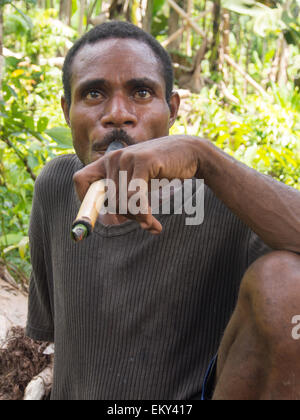 La giungla, Indonesia - 14 Gennaio 2015: uomo fuma un sigaro mentre attraversano la giungla Foto Stock