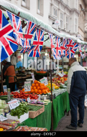 Raccordo di plastica bandiere appendere al di sopra di un mercato di frutta e verdura in stallo Loughborough. Foto Stock