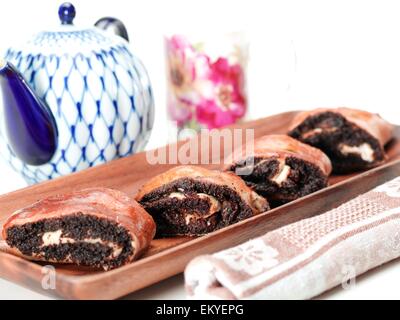 Poppyseed fresca torta di caffè sul vassoio di servizio con un asciugamano davanti e teiera in retro su sfondo bianco Foto Stock