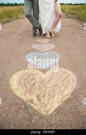 Simboli di cuore sagomato con matite colorate su terra e due persone nell'amore. Lo stile di vita e il concetto di sentimenti Foto Stock