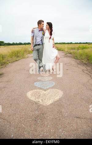 Simboli di cuore sagomato con matite colorate su terra e due persone nell'amore. Lo stile di vita e il concetto di sentimenti. Foto Stock