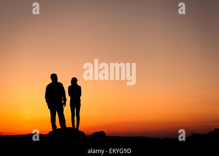 Silhouette di felicità famiglia contro bellissimo cielo colorati. Tramonto d'estate. Paesaggio Foto Stock