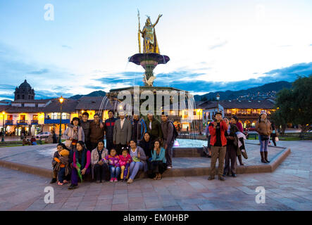 Perù Cusco. I peruviani che posano per una foto di gruppo sotto la statua del re inca Pachacutec sopra Fontana in Plaza de Armas. Foto Stock