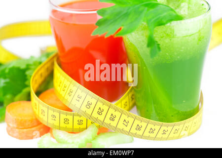 Nastro di misurazione, bicchiere di succo di sedano e un bicchiere di succo di carota Foto Stock