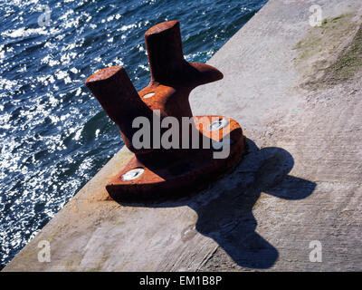 Un arrugginito bollard su un molo, utilizzato per ormeggio barche. Foto Stock