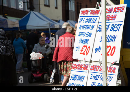 Nuneaton street market con indicazioni per carni fresche con gli acquirenti in background Foto Stock