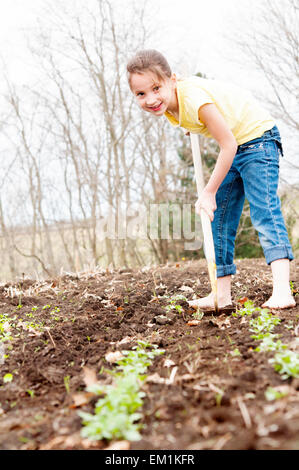 Ragazza contribuendo a zappa il giardino Foto Stock