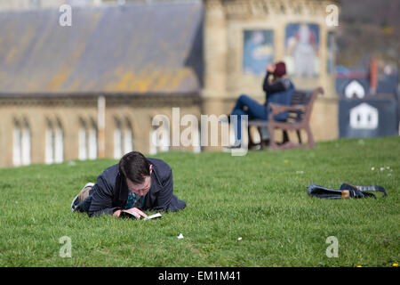 Aberystwyth, Wales, Regno Unito. Il 15 aprile 2015. Meteo. Un uomo che legge un libro in sole di primavera sull'erba dal vecchio collegio Aberystwyth Credito: Alan Hale/Alamy Live News Foto Stock