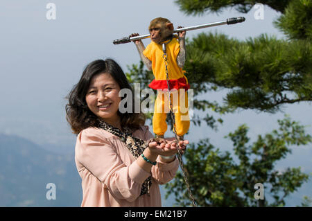 Scimmia macaco pone con turisti cinesi su Huaguo Mountain Scenic Area, Lianyungang, Jiansu Provincia, Cina. Foto Stock