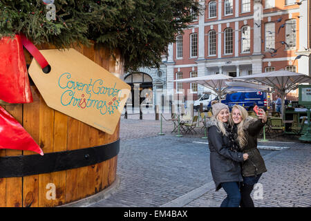 Due giovani donne che assumono selfies con il telefono cellulare e il Covent Garden di Londra, Regno Unito Foto Stock