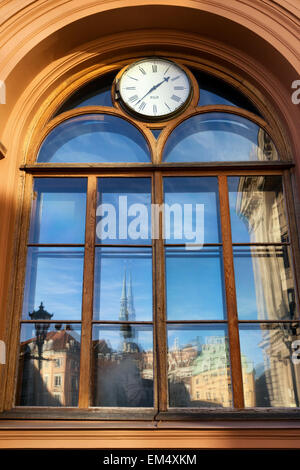 La riflessione della città vecchia in piazza Duomo a Riga in un edificio con un orologio sullo scambio. Riga. Lettonia Foto Stock