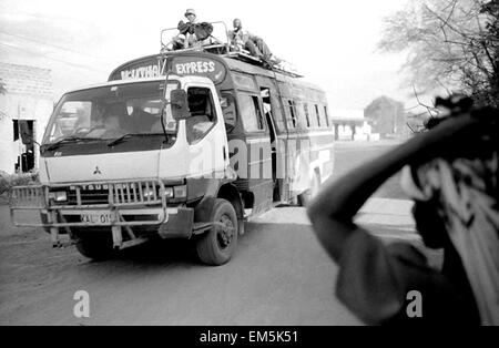 Un matatu e una donna in una strada polverosa nelle zone rurali del kenia. Paesaggio. Le infrastrutture in Kenya sono molto poveri. Le strade non sono pav Foto Stock