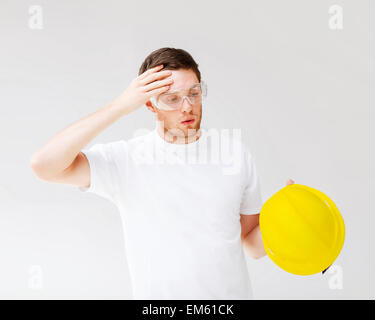 Builder maschio in occhiali di sicurezza prendendo il largo casco Foto Stock