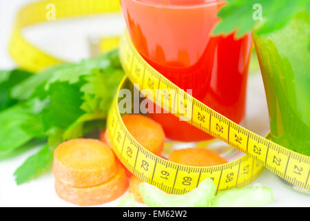 Nastro di misurazione, bicchiere di succo di sedano e un bicchiere di succo di carota Foto Stock