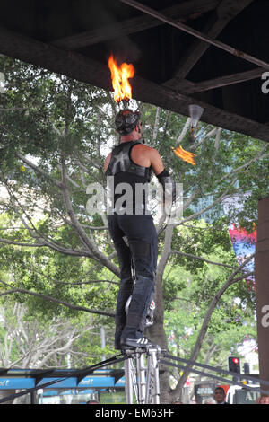 L'artista di strada giocoleria con fiaccole ardenti mentre in piedi su un cavalletto durante una performance al Circular Quay, Sydney, Australia. Foto Stock