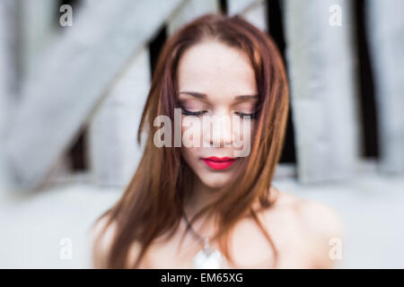 Ritratto di un i capelli rossi piuttosto giovane signora con gli occhi chiusi vicino edificio abbandonato in campagna.immagine è stata scattata con Lensbaby Foto Stock