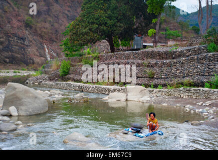 Filippine donna bucato sul fiume in modo tradizionale. Più di un quarto Foto Stock