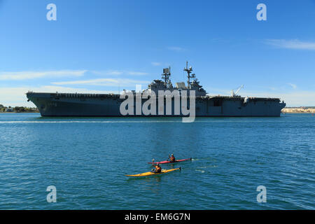 Una fotografia di due kayakers davanti la USS America (LHA-6), nella Baia di San Diego, come si vede dal Seaport Village. Foto Stock