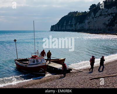 Vista di una imbarcazione per la pesca e lo sbarco dei passeggeri a un piccolo molo in legno sulla ripida spiaggia di ciottoli a birra East Devon England Regno Unito Foto Stock