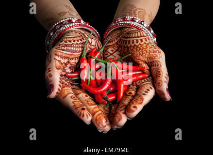 Donna mani con henna holding peperoncino rosso isolato su sfondo nero con tracciato di ritaglio Foto Stock