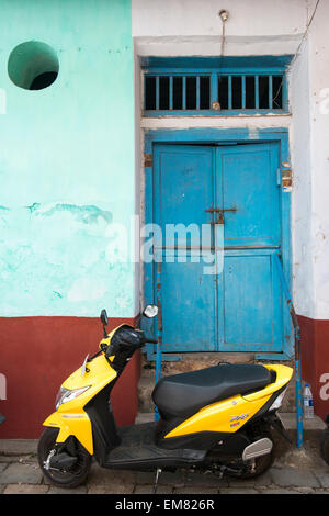 Un ciclomotore parcheggiato contro un dipinto di blu porta in città Giudeo, Fort Kochi, Kerala India Foto Stock